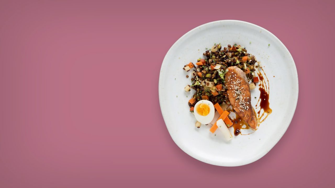 A flatlay photo of a dinner plate on white ceramic with a solid background color.