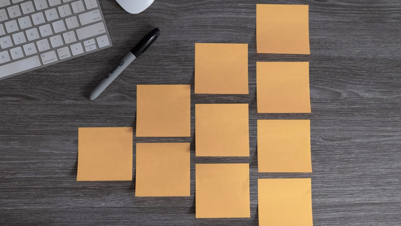A group of blank sticky notes on a table along with a felt-tip marker