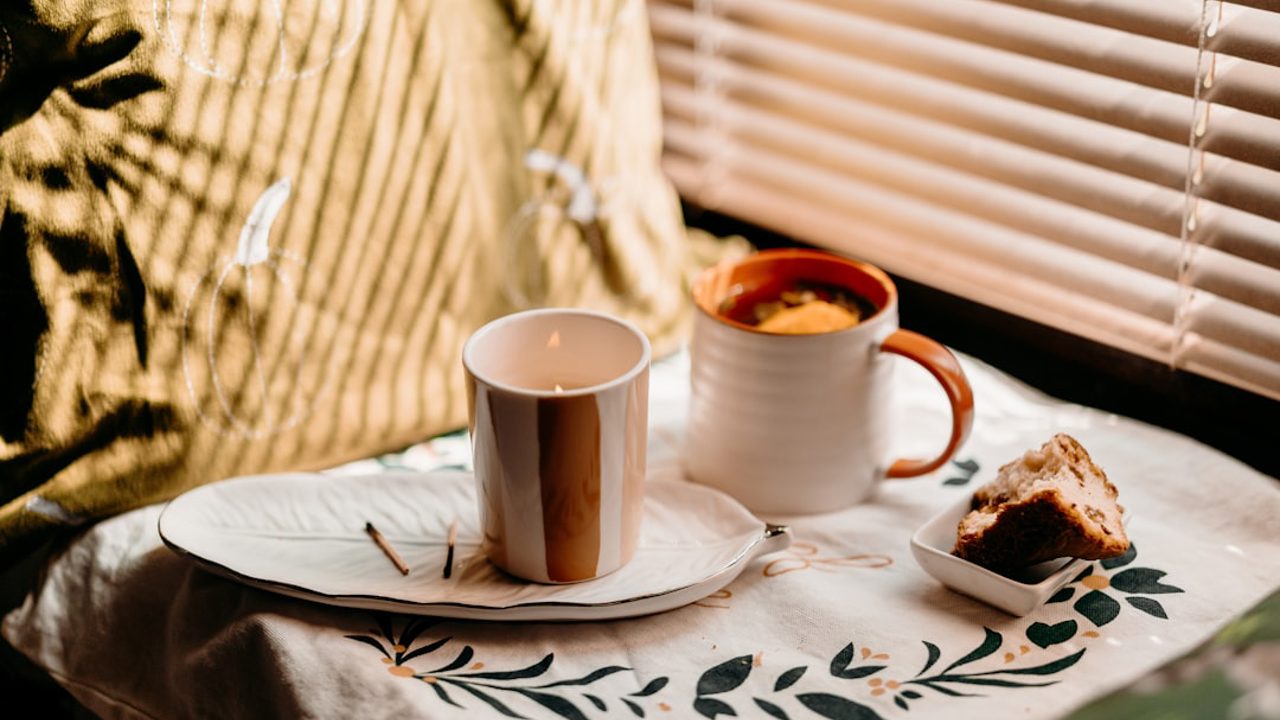 Candles, tea, and cookies on a windowsill in sunlight, autumn atmosphere